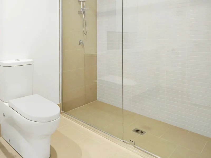 Light beige tiled shower and toilet