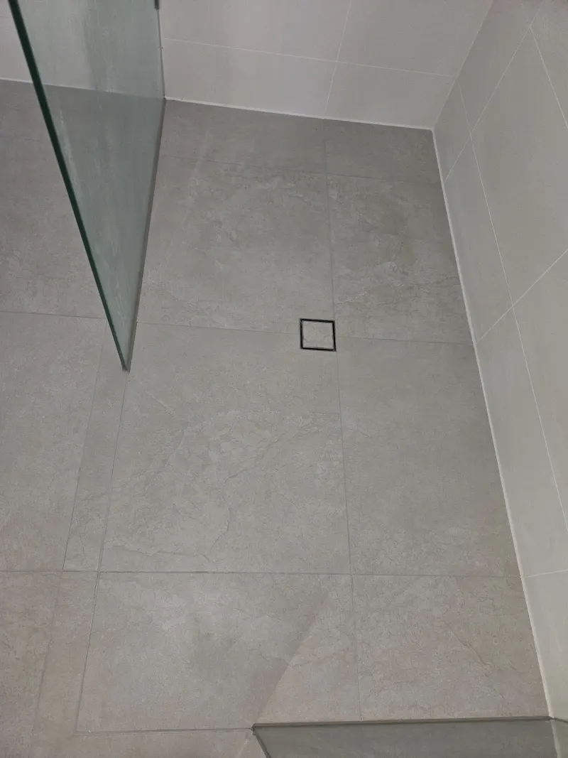 Client shower with grey tiles, glass screen and renewed floor joints