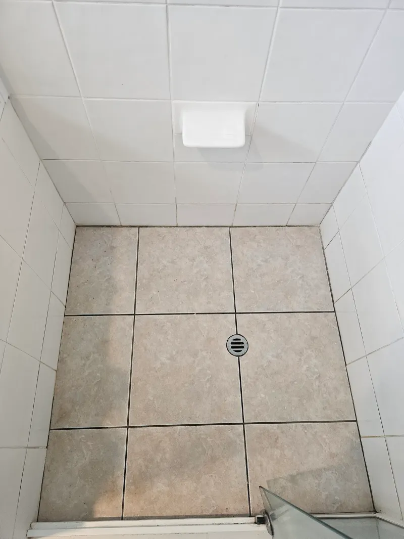 Tan tiled shower floor with a central drain