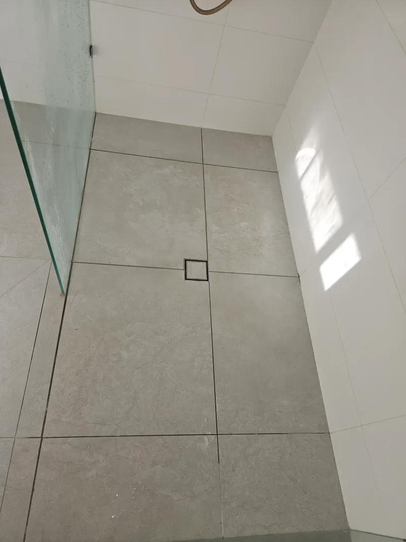 Pale tiled shower floor with a square drain
