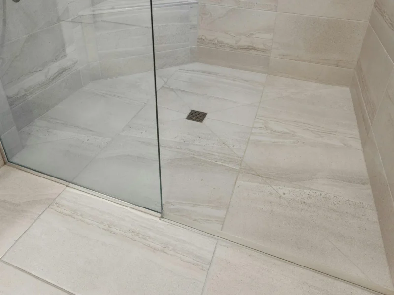 Light grey tiled shower floor and drain